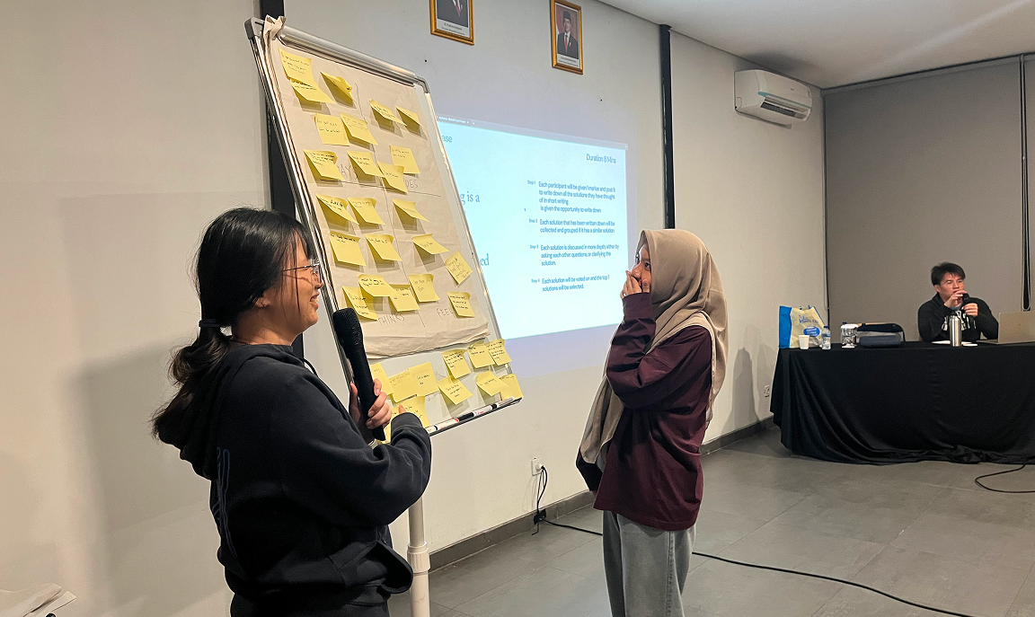 Two WidaTech team members presenting ideas on a wall covered with notes